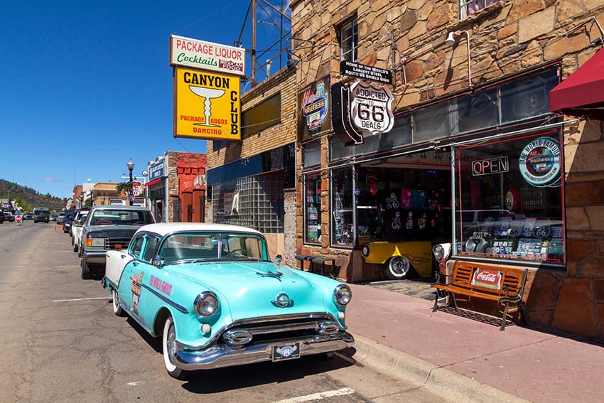 Williams, Arizona, USA: May 24, 2019: Street scene with classic car in front of souvenir shops in Williams, one of the cities on the famous route 66