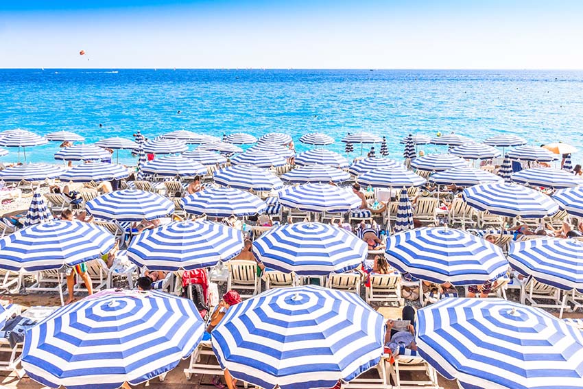 NICE, FRANCE - AUGUST 23: Tourists enjoy the good weather at the beach on August 23, 2015 in Nice, France. The beach and the waterfront avenue, Promenade des Anglais, are full almost all the year.